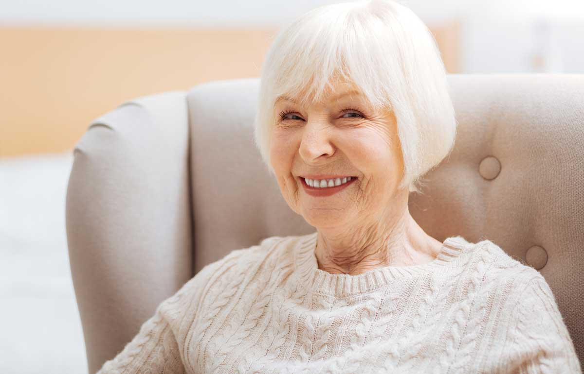 Elderly woman sitting in high back armchair