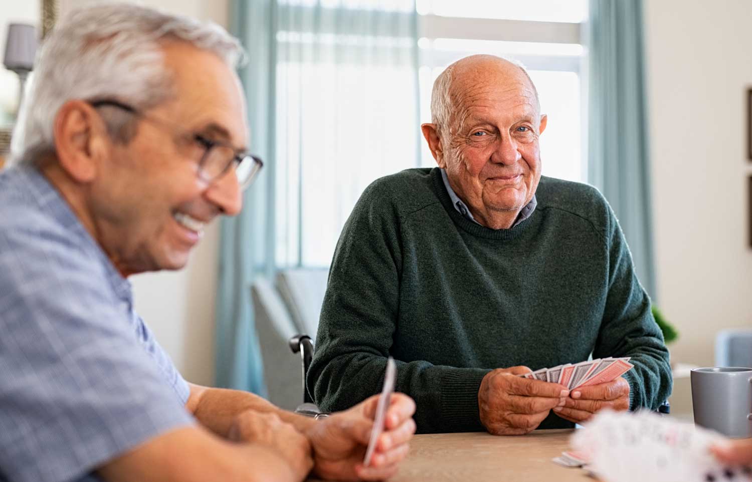 Elderly men playing cards in retirement village community centre