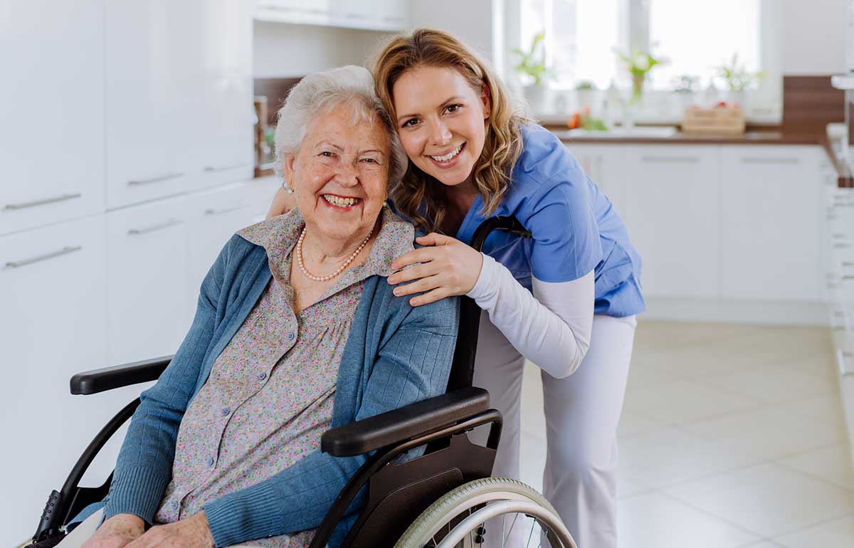 Elderly woman in wheelchair with carer