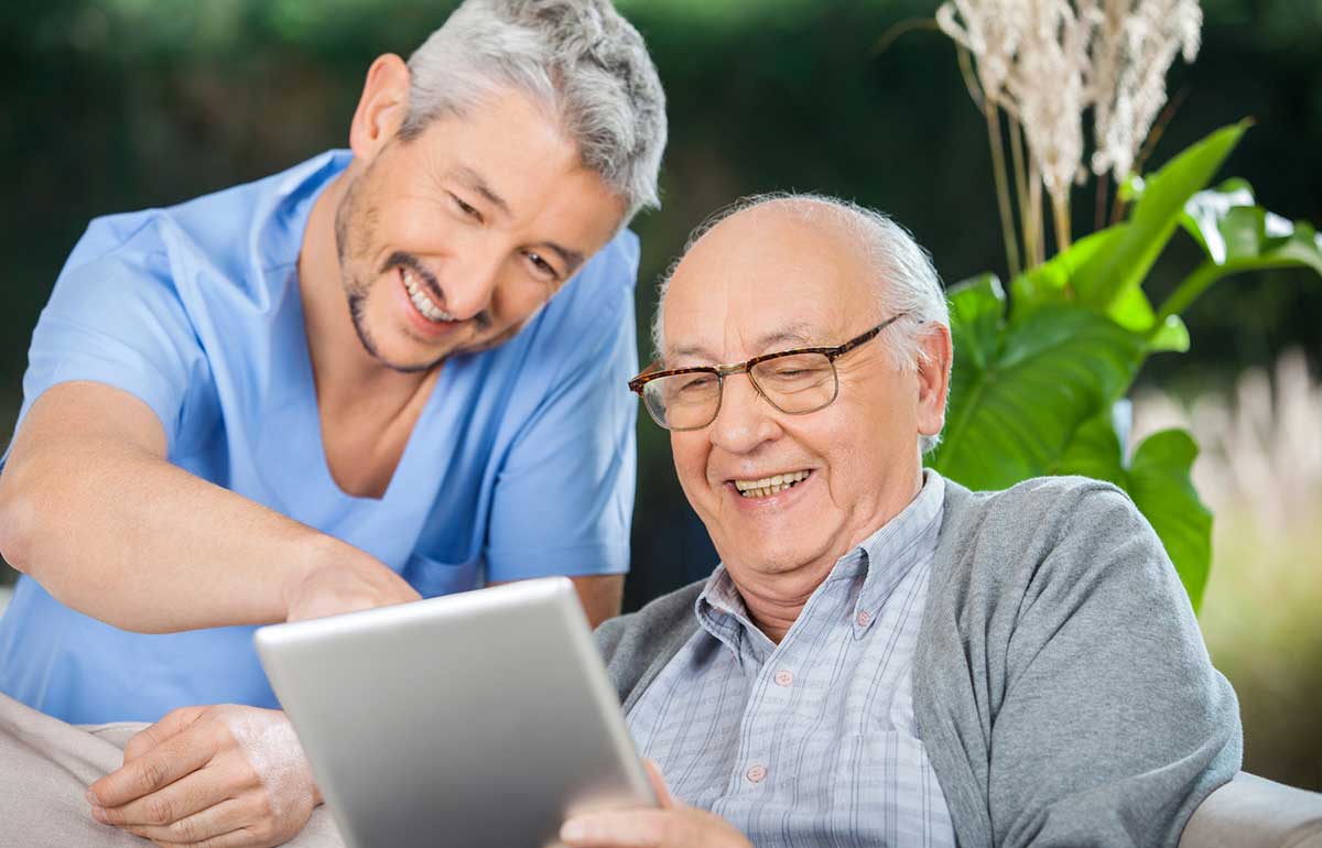 Health care provider and elderly man looking at tablet