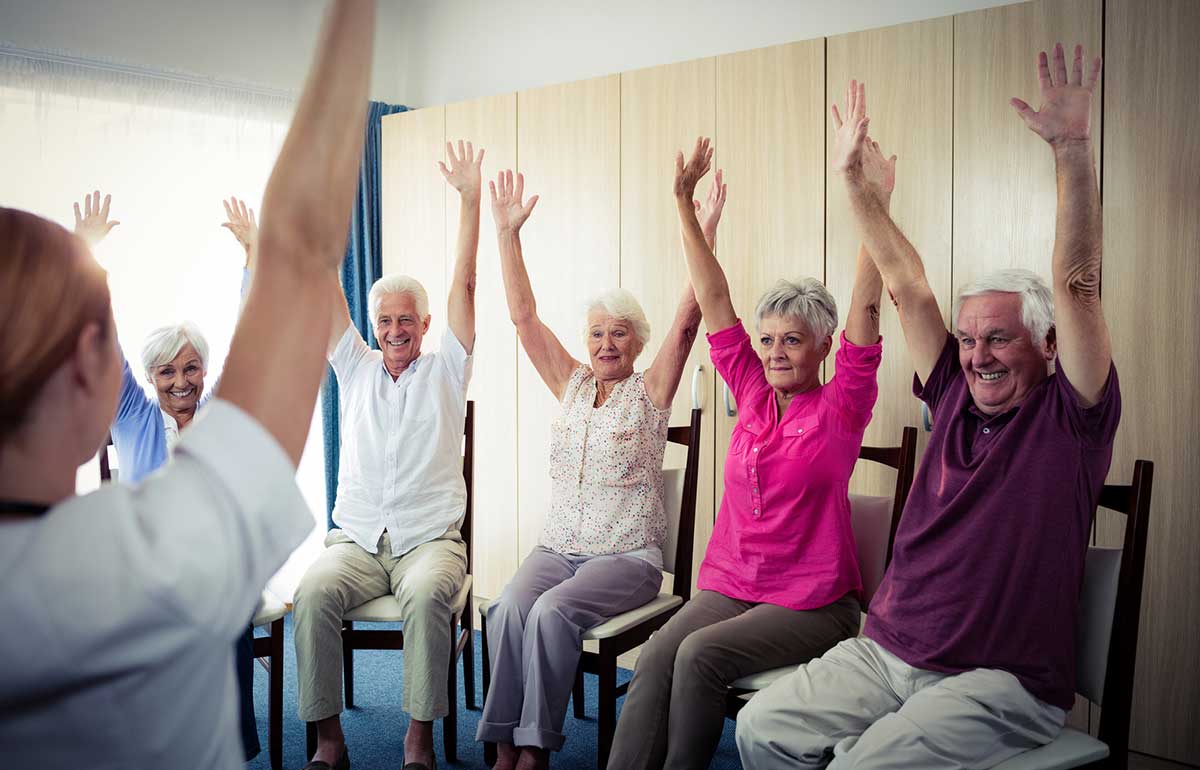 Elderly people doing seated exercise in aged care